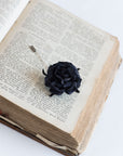 Blacl rose lapel pin on the open book