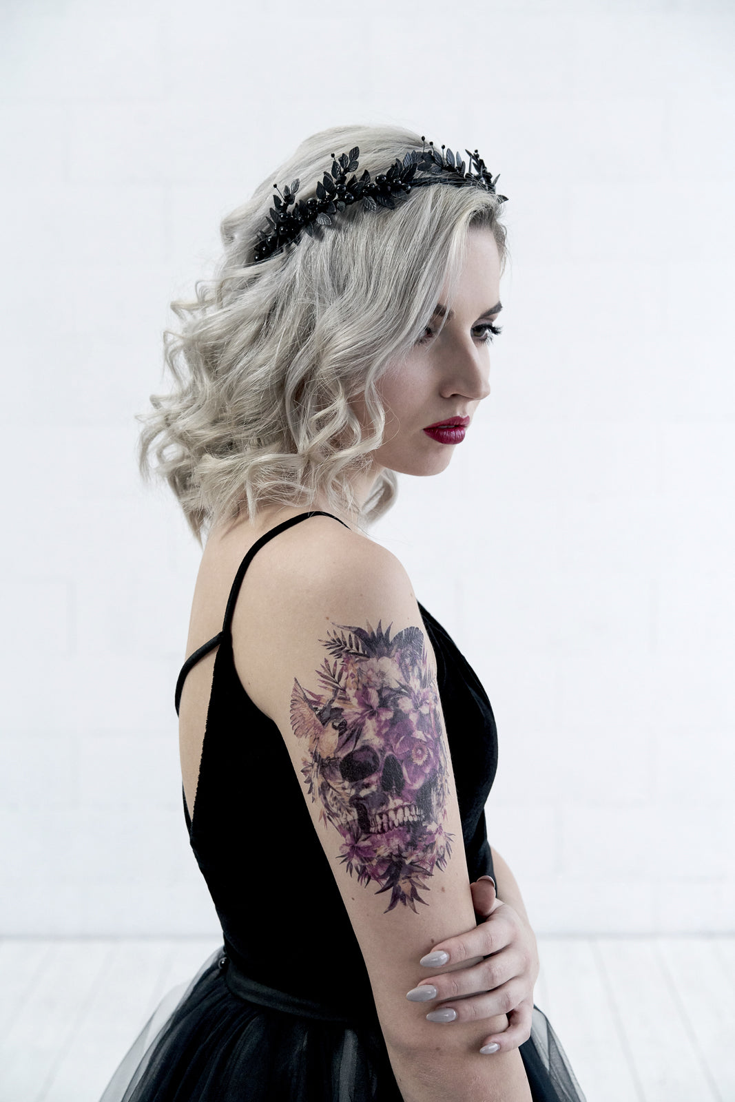 Side view of the LZZY black laurel crown on a white background, showing the matte black leaves and dark pearl accents.