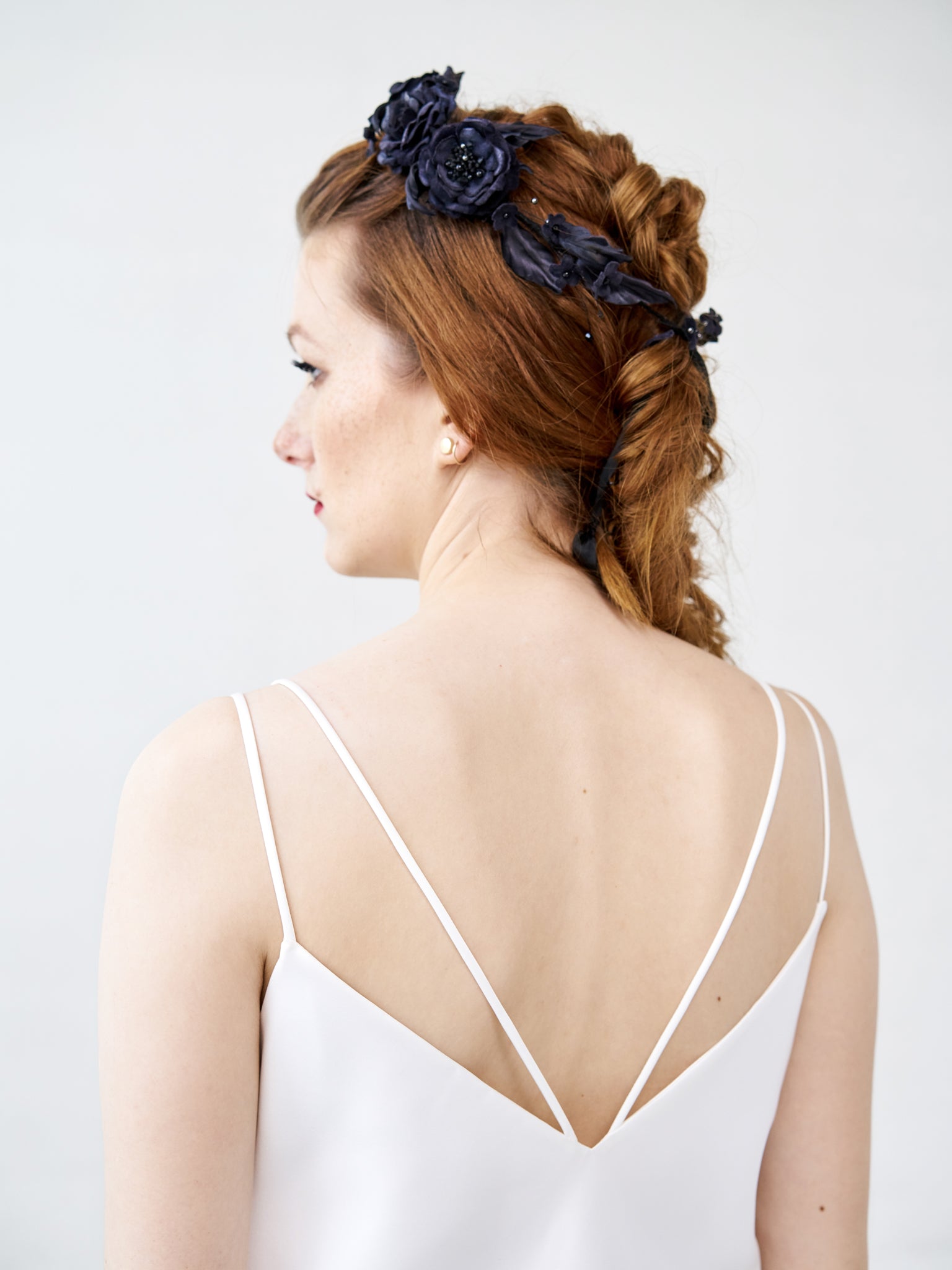 View of a bride with a complex braid hairstyle featuring the FIONA black silk velvet rose crown, showing the flexible integration of hand-sculpted flowers.