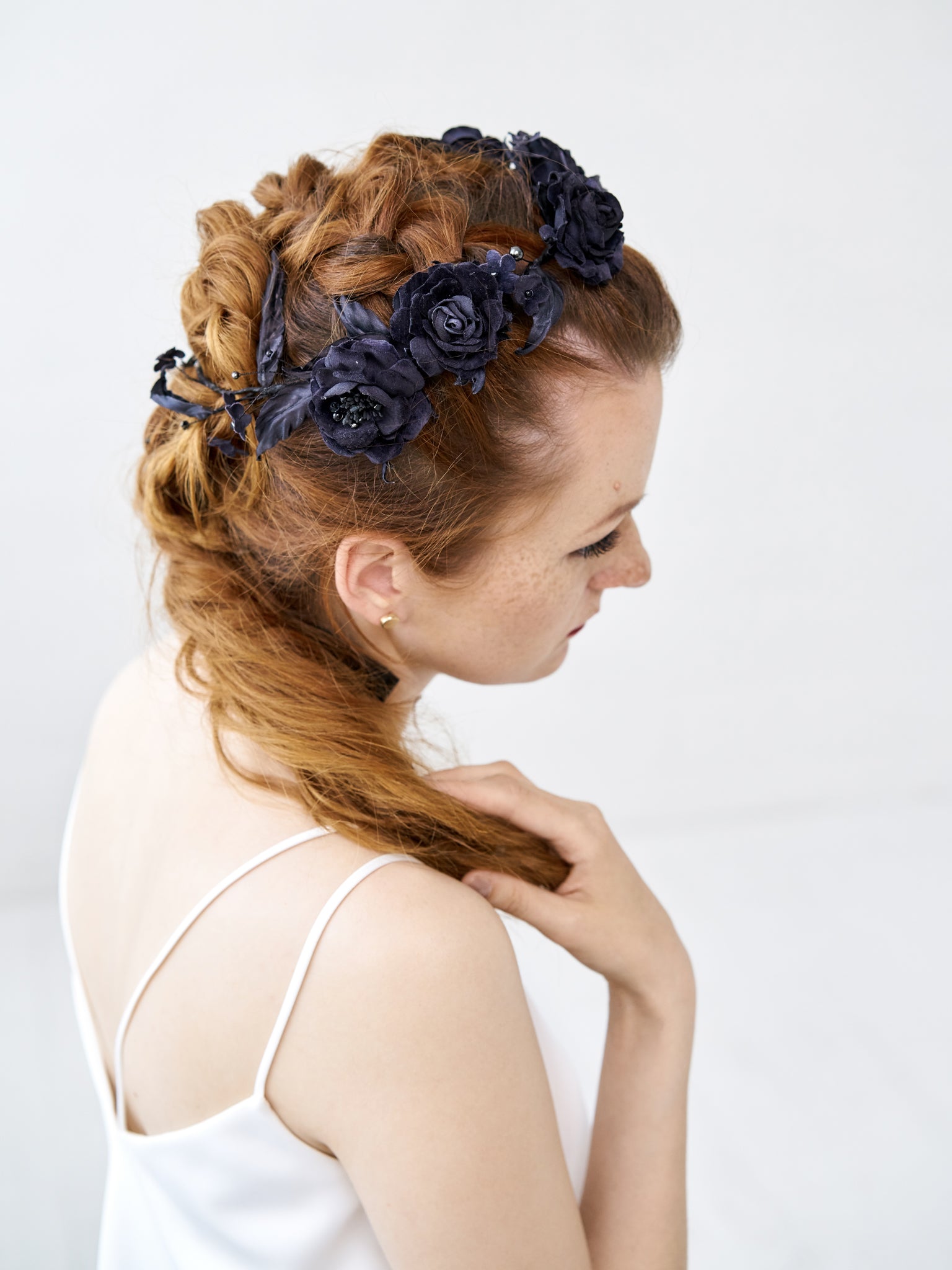 View of a bride with a complex braid hairstyle featuring the FIONA black silk velvet rose crown, showing the flexible integration of hand-sculpted flowers.