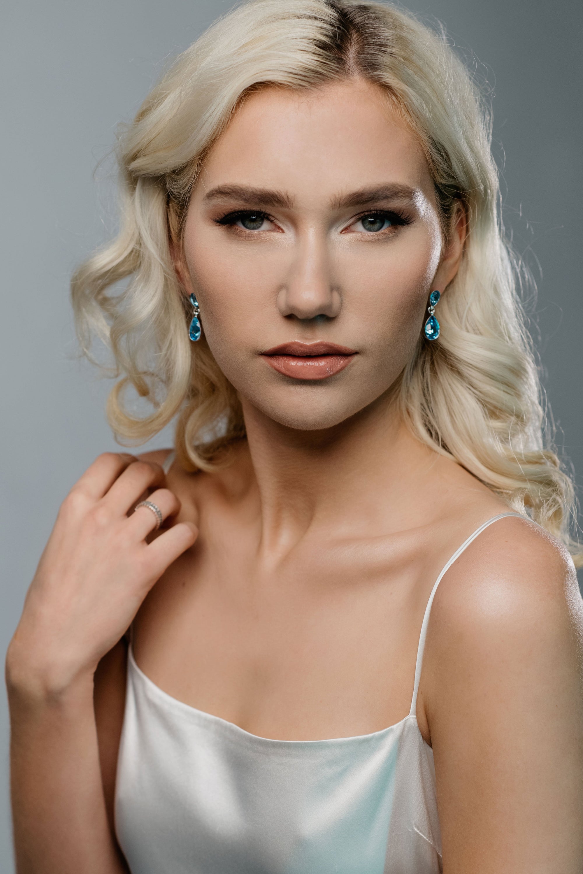 Model wearing REGN bridal drop earrings in aquamarine crystal and silver finish, elegant and minimalist