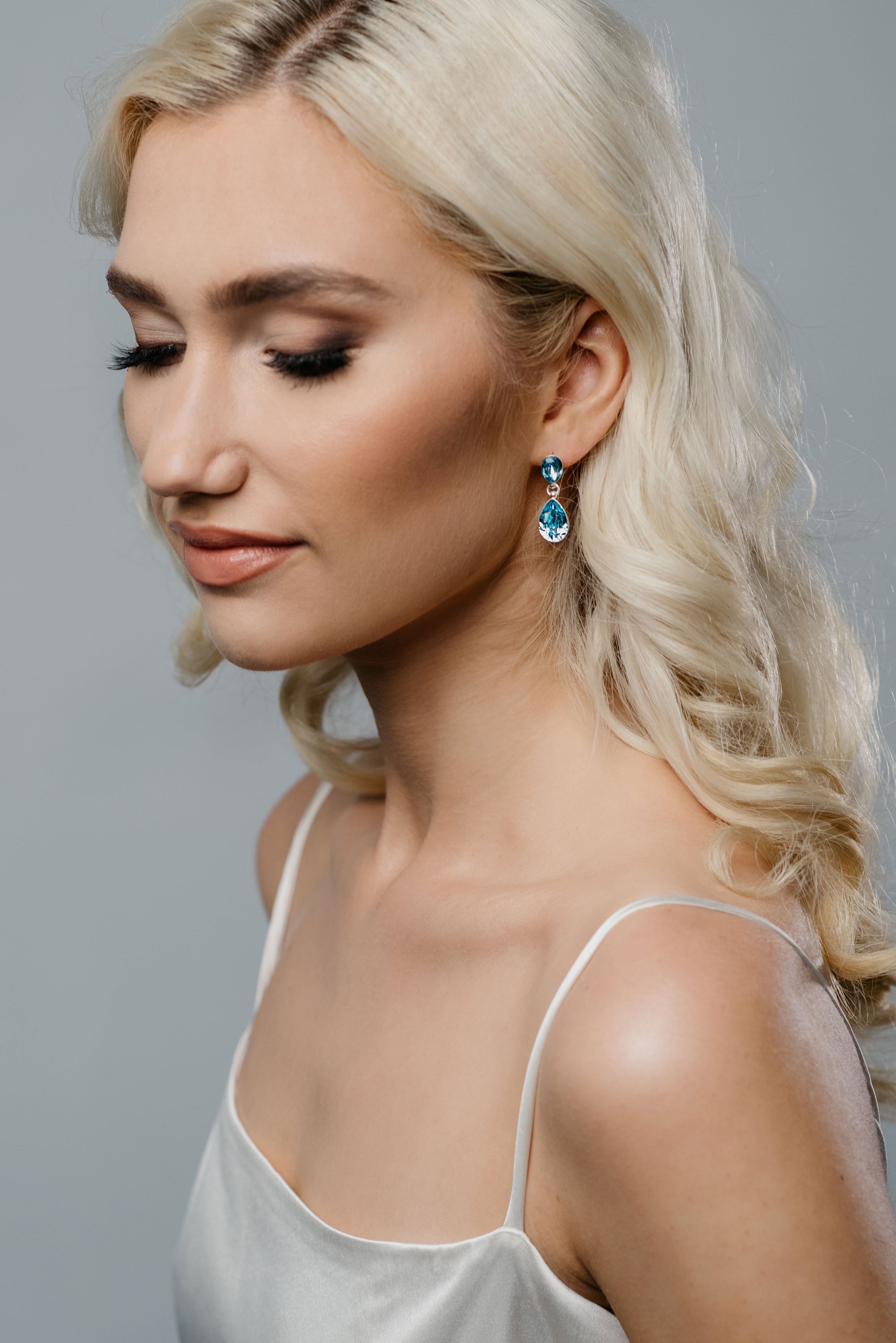 Model wearing REGN bridal drop earrings in aquamarine crystal and silver finish, elegant and minimalist