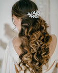 A bride with long brunette curls wearing the LIUCINA white velvet jasmine hair vine, demonstrating how the flexible floral vine shapes around a half-up bridal hairstyle.