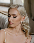 Bride wearing PERELLA baroque pearl drop earrings with white opal crystal accents