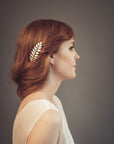 Gold laurel leaf hair comb with off-white enamel and pearl accents worn in a loose bridal updo