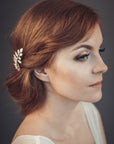 Gold laurel leaf hair comb with off-white enamel and pearl accents worn in a loose bridal updo
