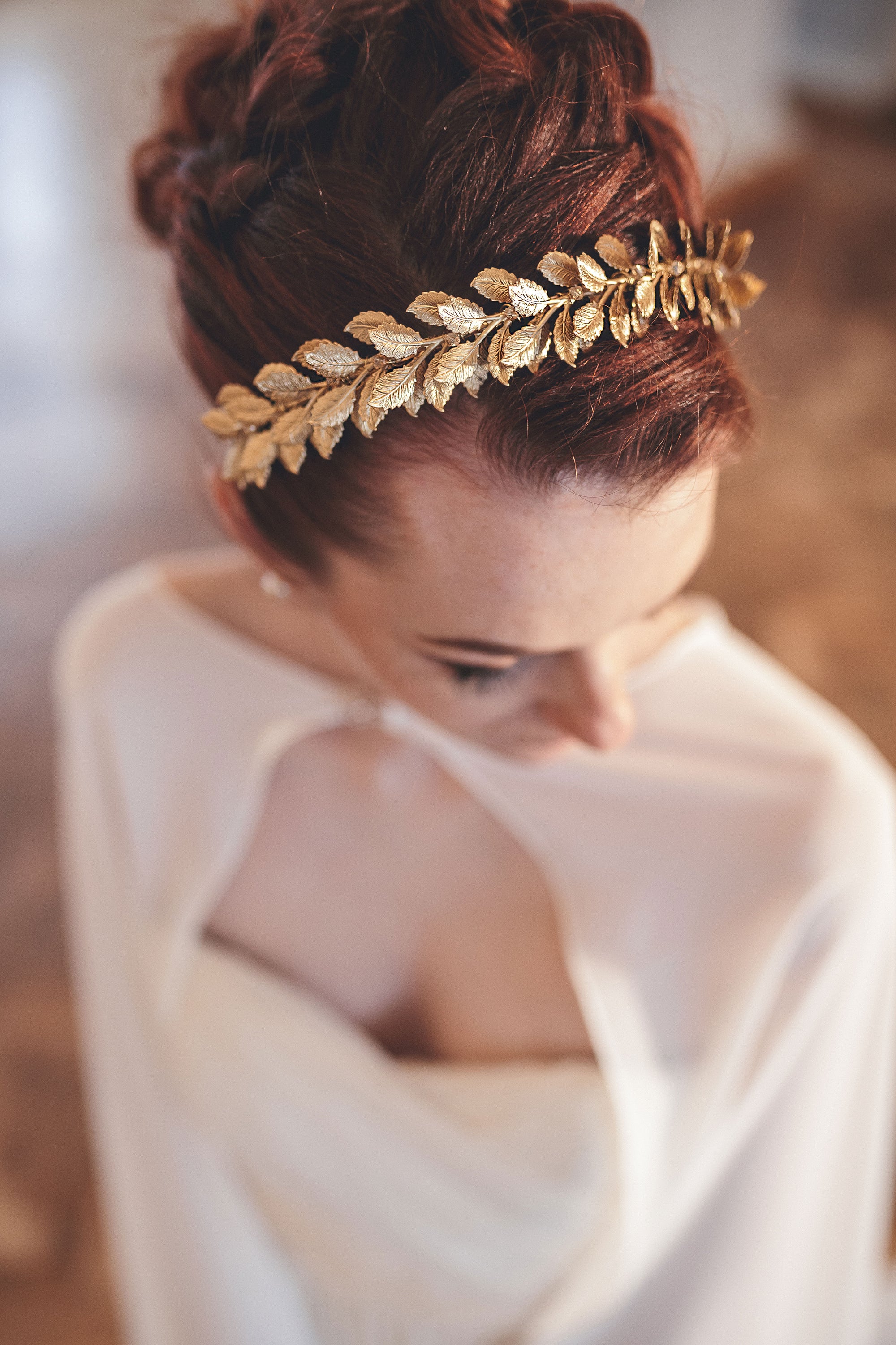 Roman-inspired gold laurel bridal headband with crystal accents worn in a low bridal updo, side profile view 