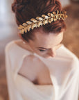 Roman-inspired gold laurel bridal headband with crystal accents worn in a low bridal updo, side profile view 