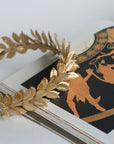 CLOTILDE gold wedding headband resting on mythology book – Roman inspired design