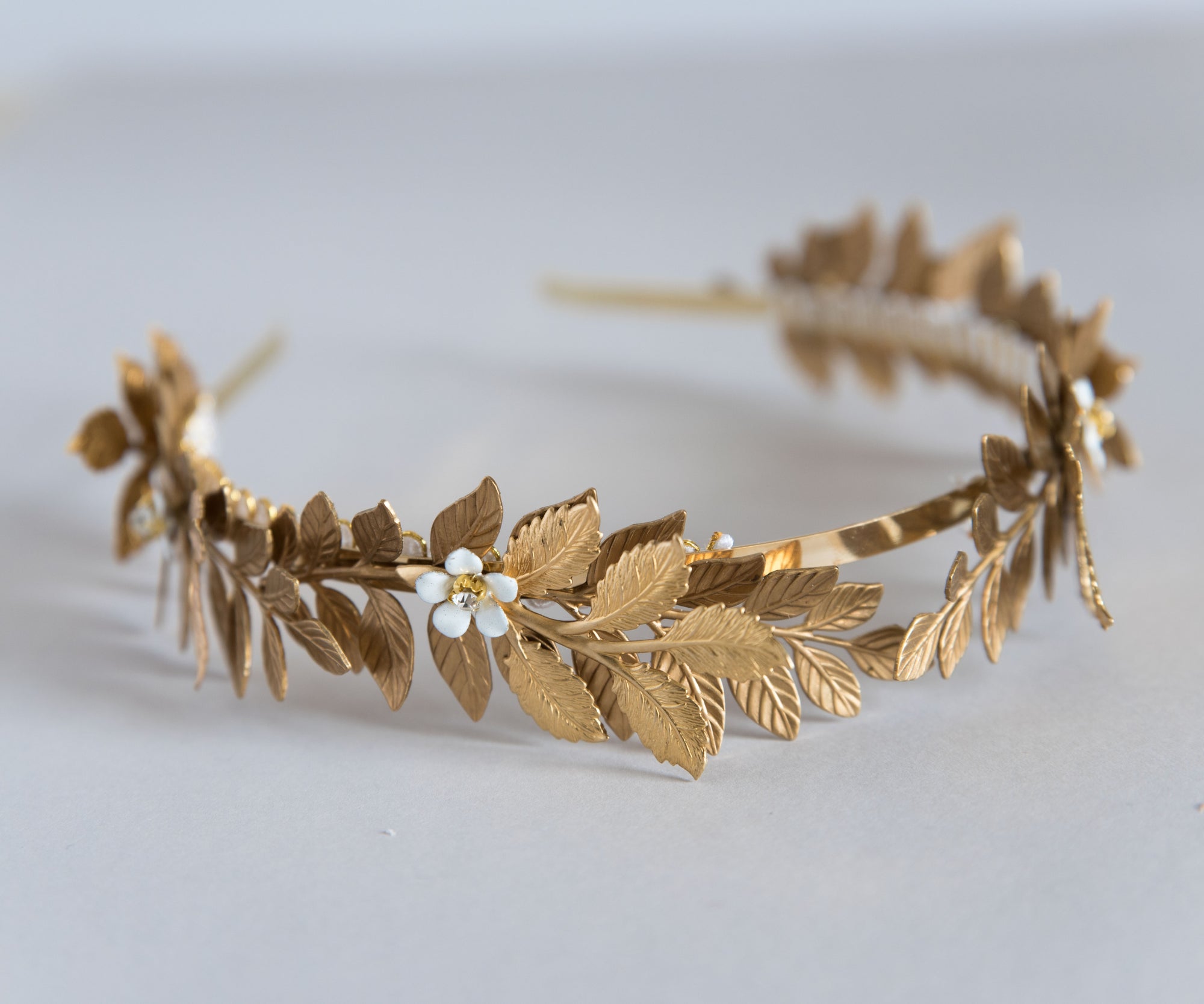 Side view of Aegle gold laurel wreath headpiece in natural light with enamel flowers