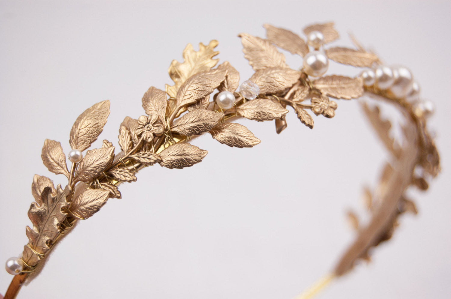 Extreme close-up of CARPO bridal headband showing the detailed veins of gold brass oak leaves and hand-wrapped ivory  pearls on a slim gold wire base.