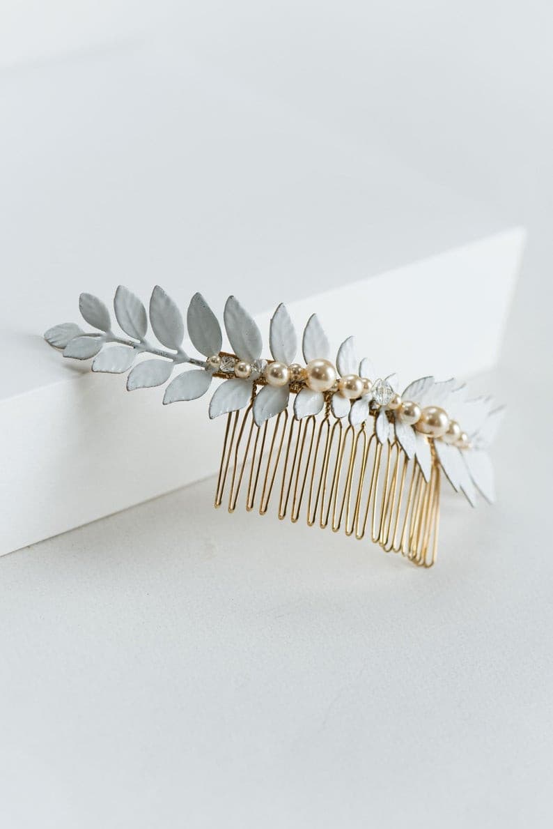Close-up of hand-enameled laurel leaves with pearl and crystal accents on a bridal hair comb