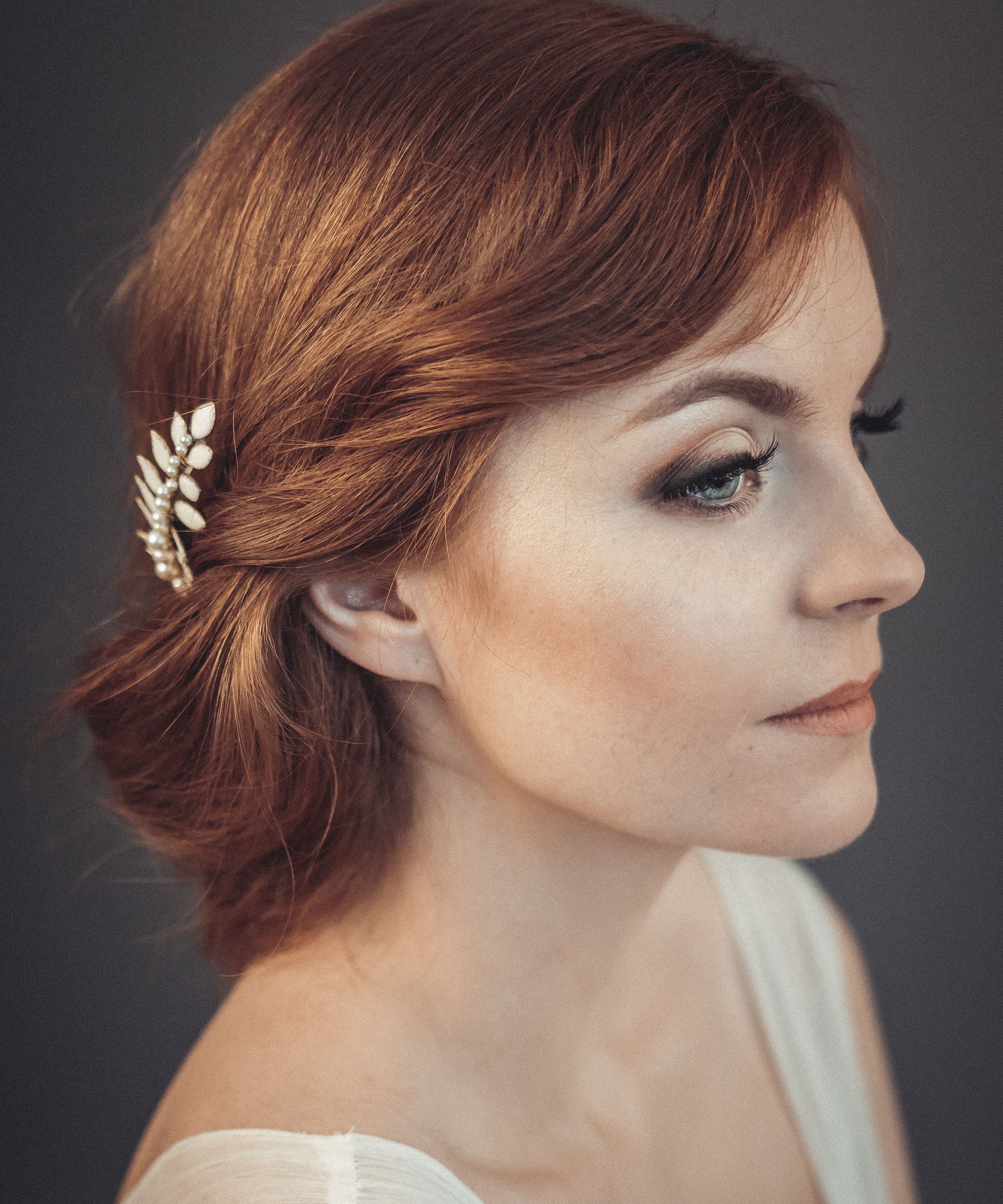 Gold laurel leaf hair comb with off-white enamel and pearl accents worn in a loose bridal updo