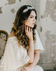 Victoria white leaf bridal tiara in hand-painted brass with pearls, shown on a bride in a minimalist editorial setting.