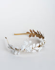 Detailed close-up of the VICTORIA bridal tiara featuring hand-painted white matte leaves, golden vine structure, and pearl accents with Austrian crystals, emphasizing the artisanal lacquer finish.