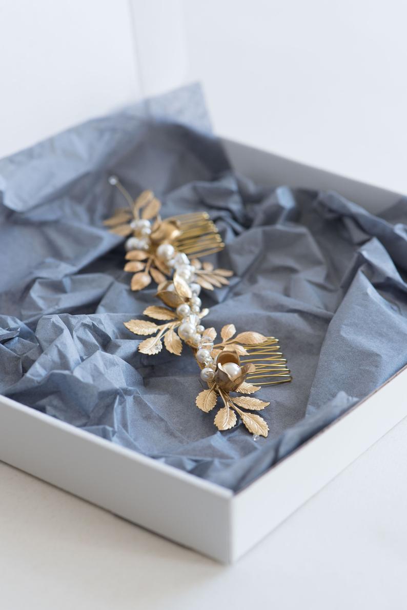 The TYCHE gold bridal hair vine with brass leaves and pearls presented in a white gift box with grey tissue paper, ready for shipping.